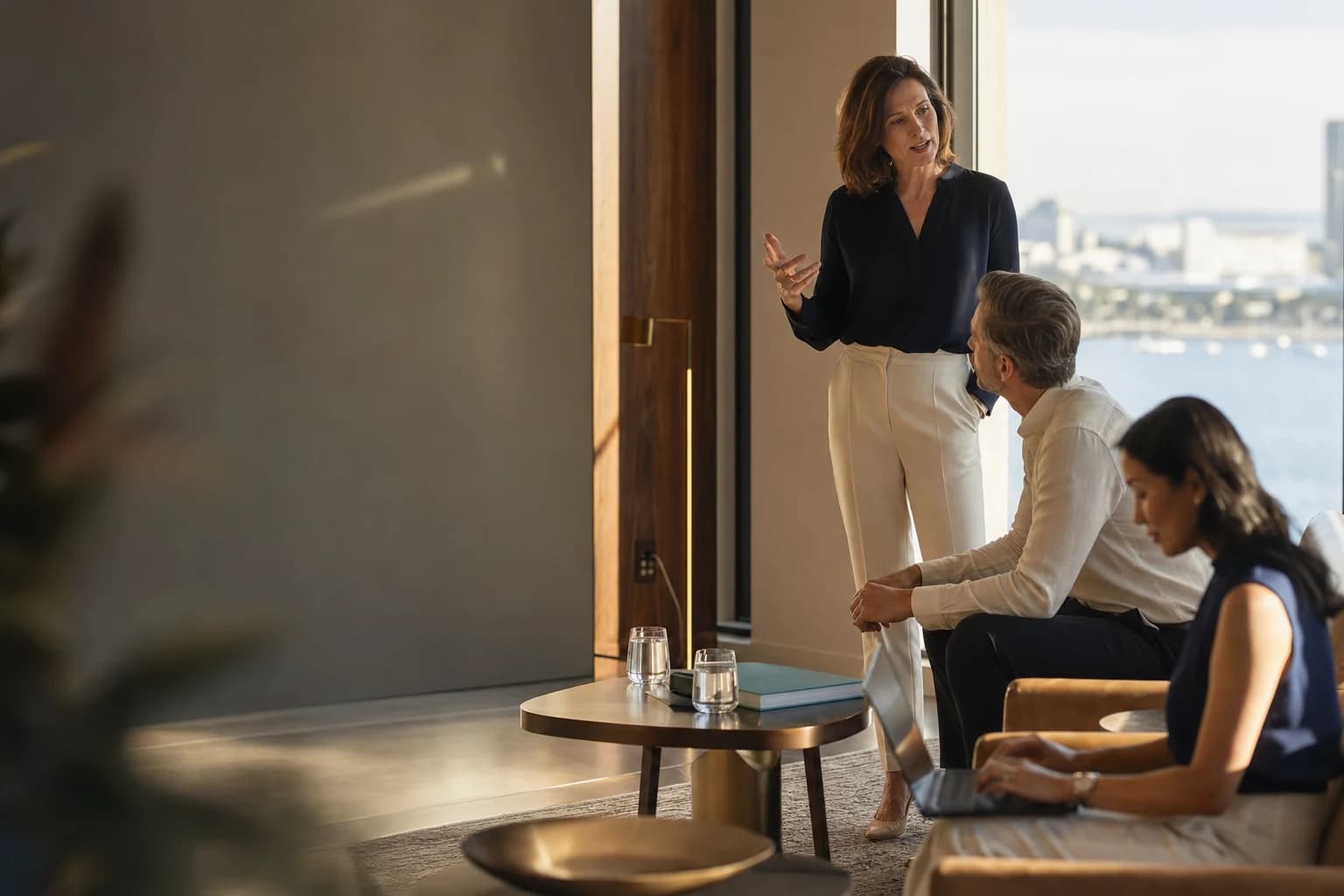 Senior Get AI Ready consultant in a Sydney executive lounge mid-conversation with a client, harbour visible through the window
